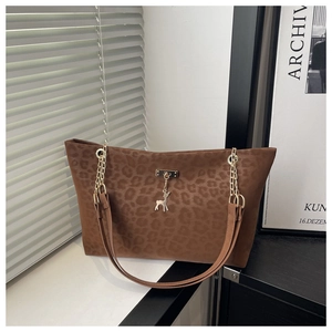 Close-up of leopard print tote bag featuring a metal chain strap and deer charm detail