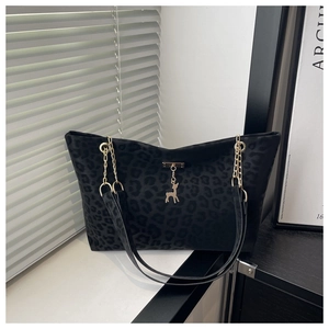 Detail of leopard print tote bag featuring a gold deer charm and metal chain strap