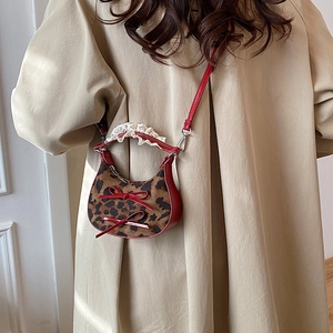 Mini leopard print crescent bag with red bows and lace handle on a khaki trench coat