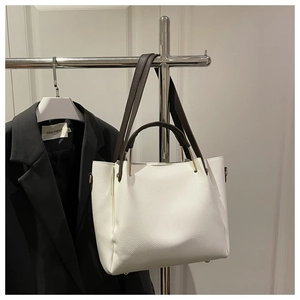 Detail of white lychee pattern leather bucket bag with brown handles and gold hardware