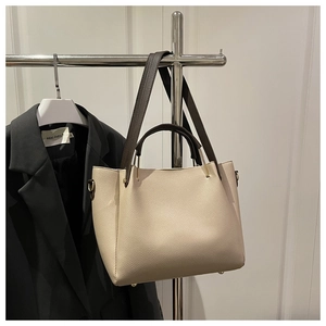 Close-up of a pebbled leather tote bag with contrast brown straps on a hanger