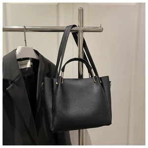 Close-up of litchi grain leather texture and metallic hardware on black tote bag