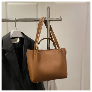 Detail view of brown pebbled leather tote with metal D-rings and sturdy handles