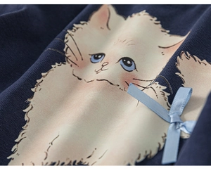 Dettaglio del tessuto a maglia blu con gatto bianco e fiocco in raso azzurro chiaro