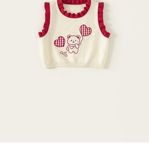 Detail of child knit vest with contrast ruffle edges and cute bear balloon embroidery