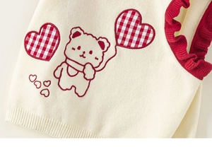 Detailed view of knitted vest with red ruffle armholes and cute bear embroidery art