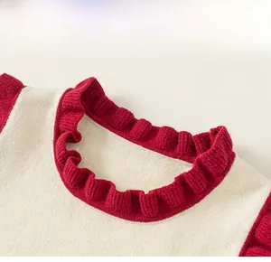 Detail of knit child sweater featuring a red ruffled collar and cream wool fabric texture