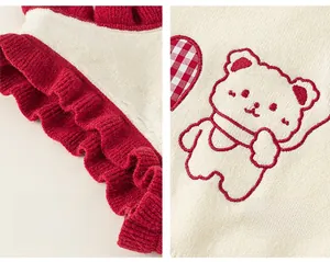 Detail of red and white knit vest with ruffled edges and cute bear embroidery