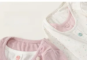 Close-up of ribbed cotton baby tops in pink and white with delicate floral dot patterns