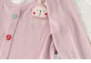 Detail of pink knit shirt with rabbit patch, colorful buttons and enchanted embroidery