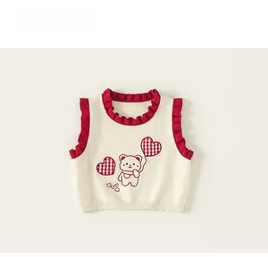 Close-up of knit vest featuring cute bear embroidery and red scalloped lace edges