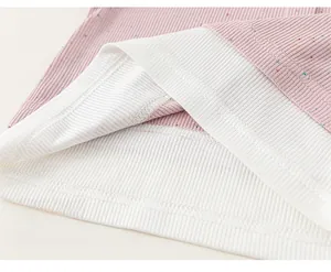 Detail view of pink knit rib fabric with colorful dots and fine stitching on children's top