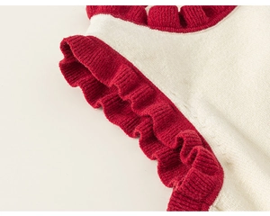 Detailed close-up of knit fabric with red ruffle trim and cream texture on sweater vest