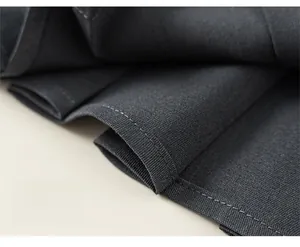 Detailansicht der präzisen Nähte und der dunkelgrauen Stoffstruktur auf dem Mädchenkleid