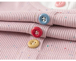 Detail view of pink nep yarn knit fabric with vibrant multi-colored buttons on a girl outfit