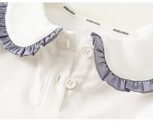 Detailansicht des weißen Rippstrick-Kragens mit grauem Satin-Rand und weißen Knöpfen