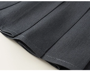 Makro-Detail von dunkelgrauem Faltenrock-Stoff mit scharfer Twill-Textur und Falten