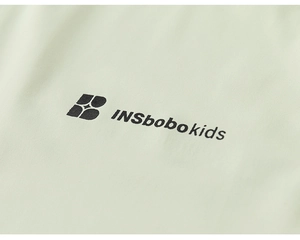 Gros plan du tissu en maille vert clair avec logo INSbobo kids sur le pantalon enfant