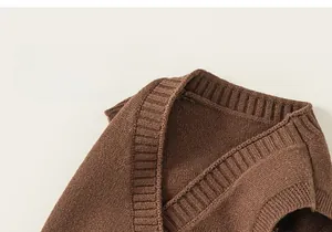 Dettaglio del gilet in maglia marrone con scollo a V e finiture a costine