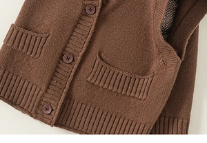 Dettaglio del gilet in maglia marrone con scollo a V a coste e trama del tessuto