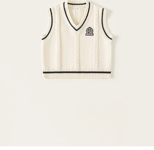 Detail of V-neck knitted sweater vest with preppy stripe trim and embroidered crest
