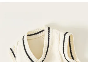 Detail of V-neck knit vest featuring striped trim and a crown embroidered badge