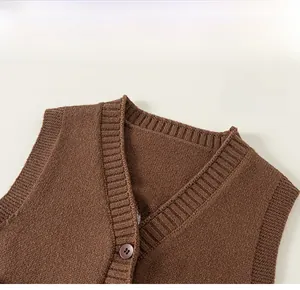 Dettaglio dello scollo a V in maglia marrone con trama a coste e bottone in resina