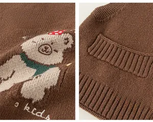 Dettaglio del gilet in maglia marrone con ricamo a orsetto e orlo a costine per bambini