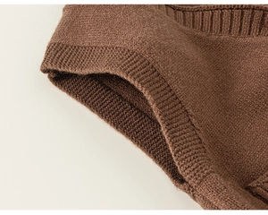 Dettaglio macro della trama in maglia marrone scuro e bordo a coste del gilet per bambini