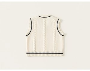 Detailed macro view of the knitted cable patterns and navy stripes on the beige vest