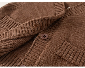 Dettaglio della trama in maglia marrone scuro e bottoni abbinati del cardigan bimbo