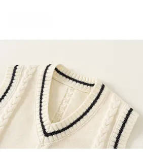 Close-up of cream V-neck knit vest with cable pattern and embroidered crest badge
