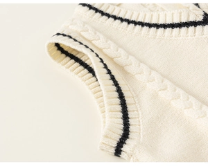 Detail of V-neck cable-knit vest with contrast black tipping on off-white fabric