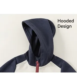 Détail d'une veste à capuche contrastée en bleu marine et beige avec une fermeture éclair rouge
