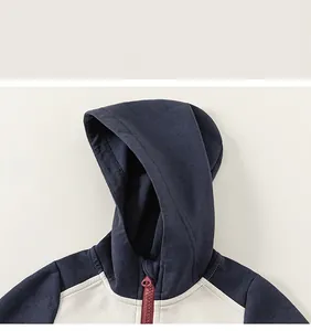 Détail du sweat à capuche pour fille avec patchwork bleu et beige et zip rouge