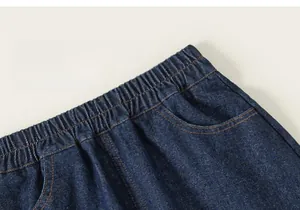 Détail de la taille élastique sur jupe en jean bleu foncé avec bouton jaune et poche