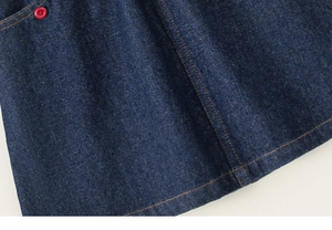 Détail d'une jupe en jean bleu foncé avec bouton rouge et texture de couture premium