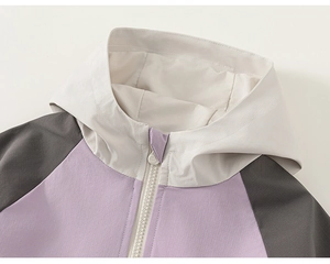 Detailed view of color-block hood and zipper on a functional outdoor jacket for girls