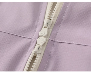 Close-up of light purple ripstop fabric and dual zippers on a girls' outdoor jacket