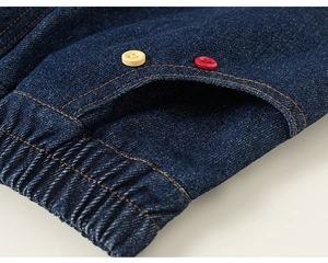 Détail d'une jupe en jean bleu foncé avec taille élastique et boutons décoratifs colorés