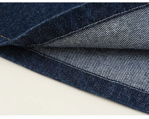 Gros plan détaillé du tissu denim bleu foncé avec coutures blanches de qualité sur l'ourlet