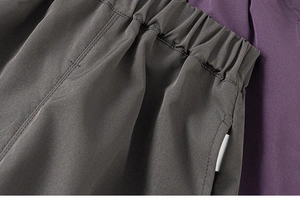 Detail of cargo pants elastic waistband and side pocket stitching in dark taupe