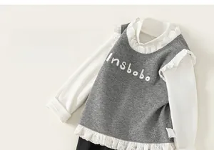 Détail du haut pour filles avec col en dentelle et gilet en tricot gris avec broderie fine