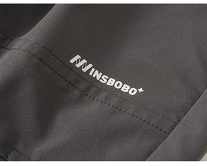 Detail of dark grey cargo pants fabric with INSBOBO logo and durable double stitching