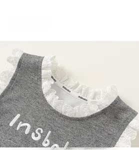 Détail d'un col en coton gris avec une fine broderie de dentelle blanche délicate