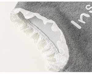 Détail du tissu en coton gris avec bordure en dentelle blanche et broderie ins