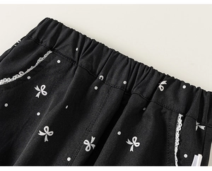 Détail du pantalon noir pour filles avec pois, nœuds et bordure en dentelle blanche