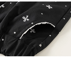 Détail macro du pantalon enfant avec pois, imprimé nœud et poches bordées de dentelle