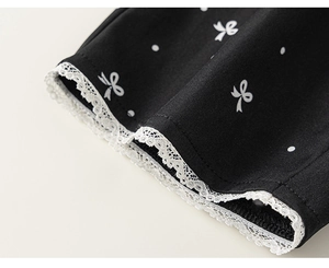 Détail du tissu noir à pois blancs, motifs de nœuds et bordure décorative en dentelle