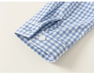 Macro shot of blue plaid shirt cuff with white button and fine stitching detail